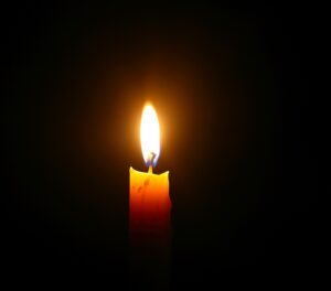 Yellow candle light burn against black background By banprik