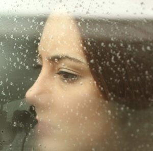 Sad woman looking through a car window By Antonioguillem