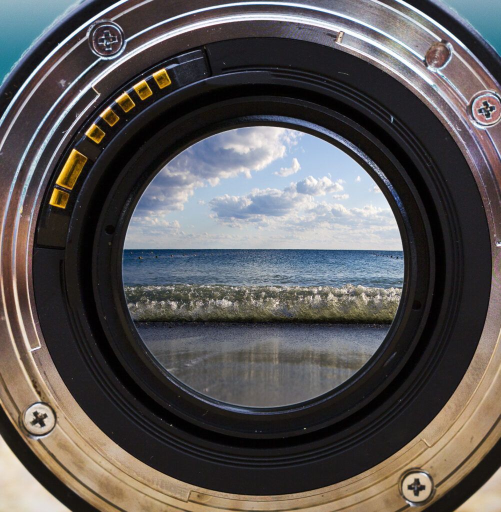 View of the sea surf through a photographic lens lying on a sandy beach on a sunny day. By Alexey