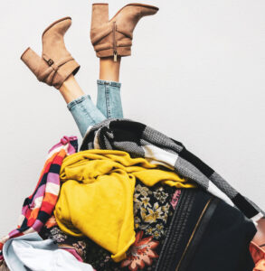 woman legs out of a pile of clothes on the floor. shopping addiction concept By ronstik